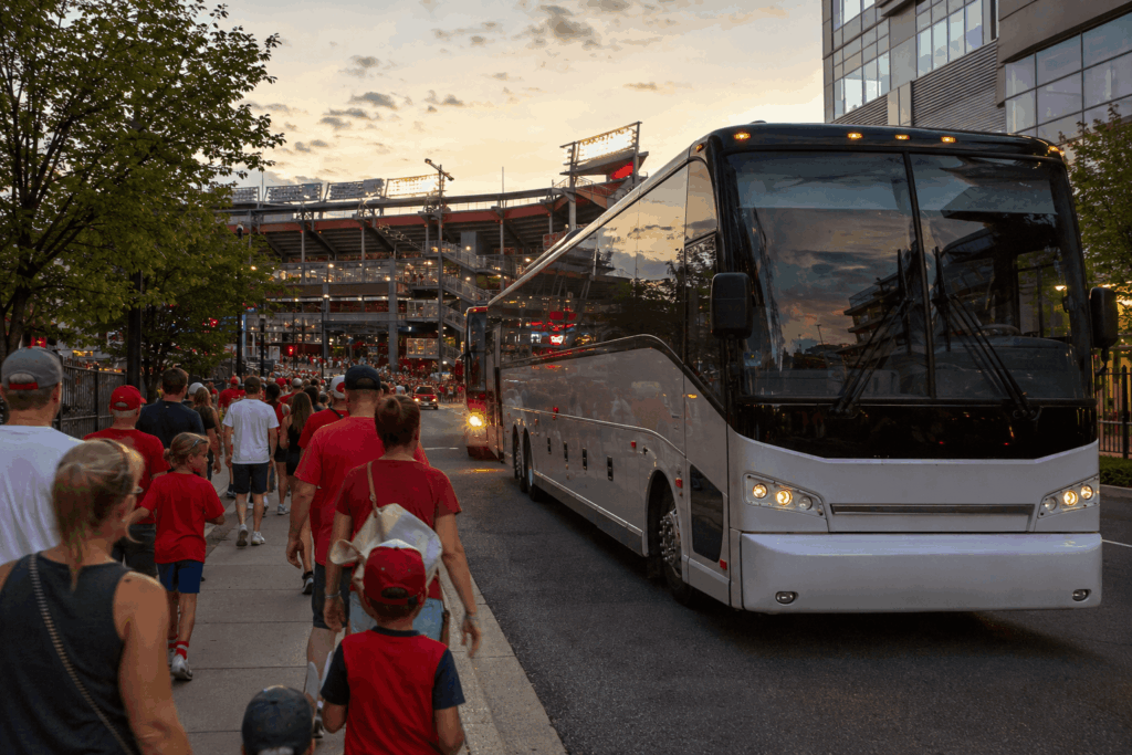 luxury charter bus arriving near nationals park in washington dc with baseball fans walking toward the stadium on a summer game night