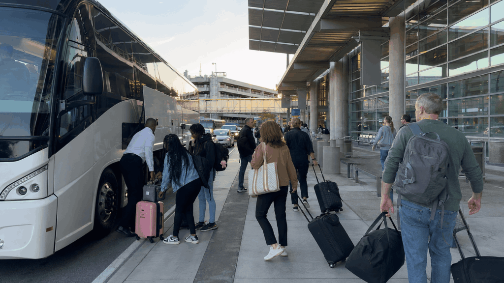 charter bus dropping off group travelers with luggage at bwi airport terminal from alexandria virginia during early morning travel