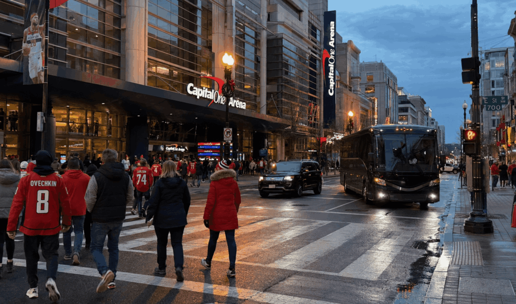 washington capitals fans crossing the street outside capital one arena with a charter bus arriving at dusk.