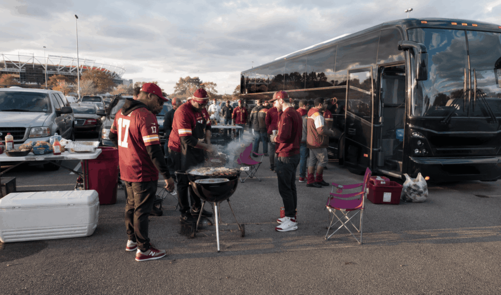 fans tailgating beside a charter bus outside northwest stadium in landover before a washington commanders game.