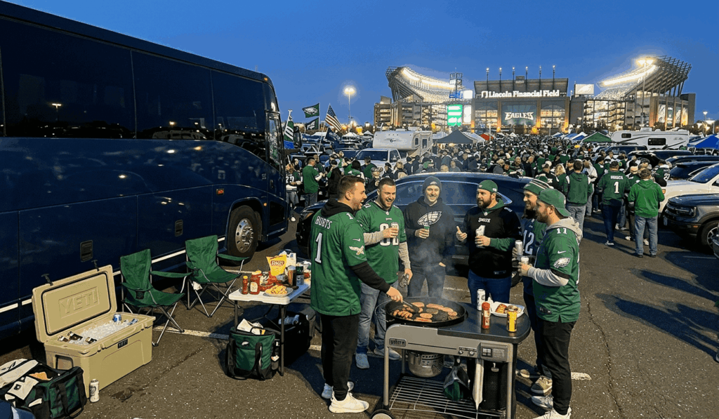 eagles fans tailgating beside a charter bus outside lincoln financial field before a night game