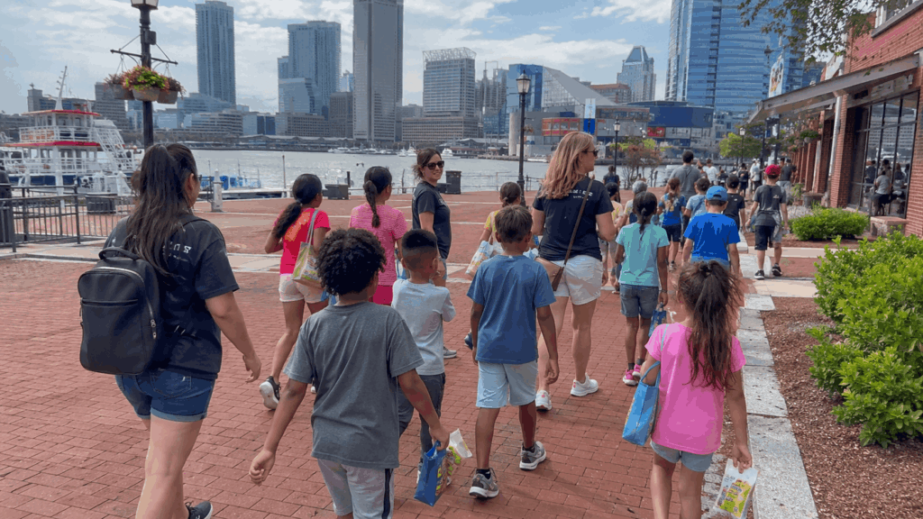 students and teachers walking along baltimore inner harbor after visiting the national aquarium during a charter bus field trip
